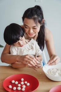 woman teaching child to make dumplings