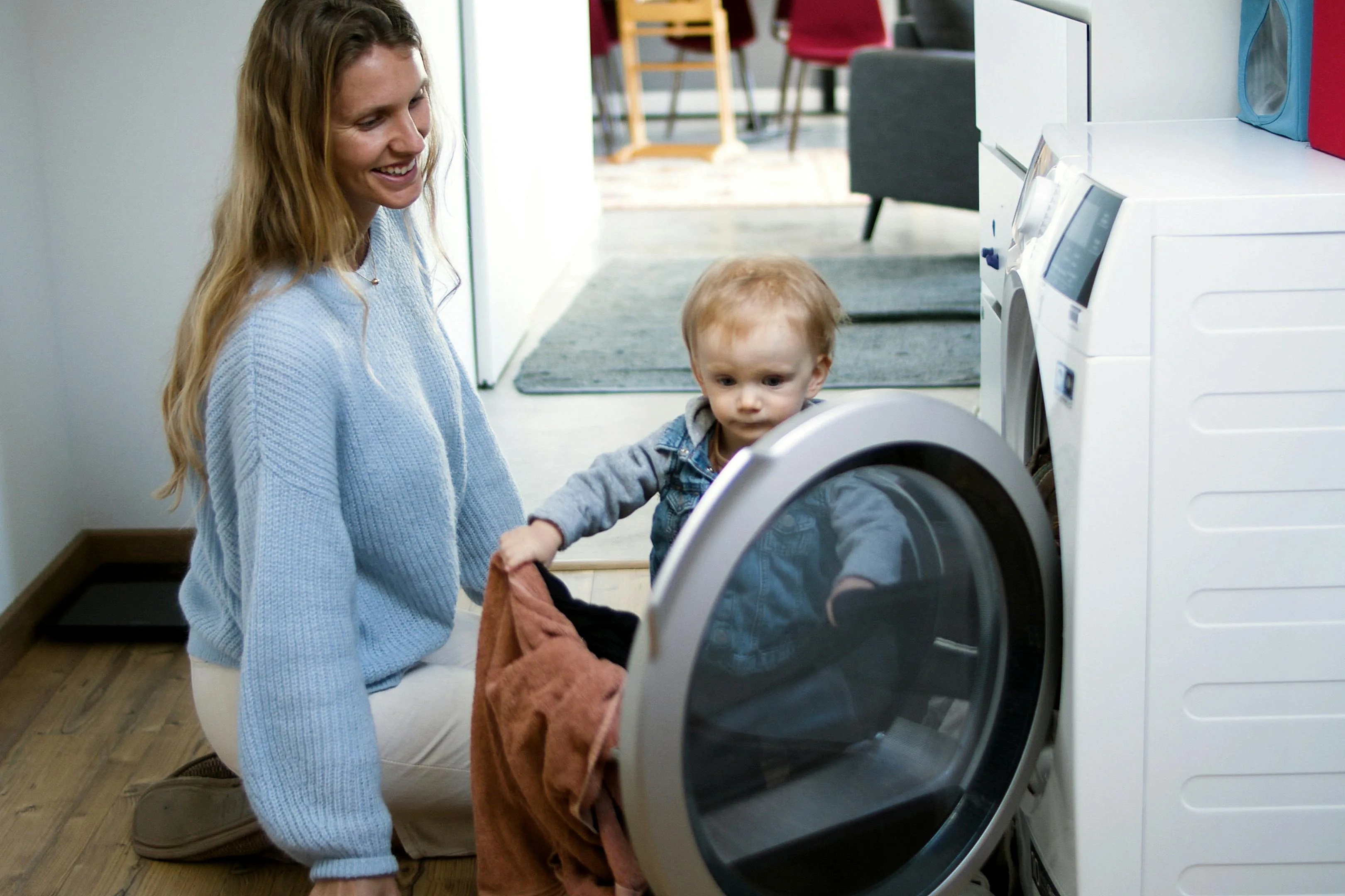 Toddler helping Au Pair with laundry