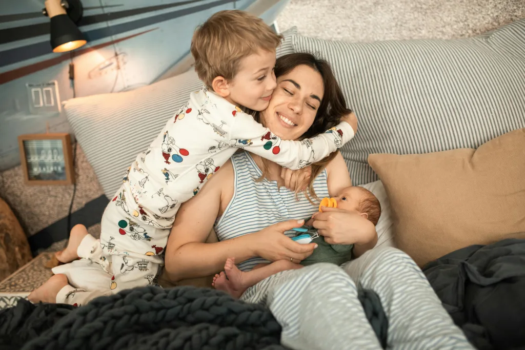 Kid hugging Au Pair holding a baby