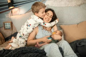Kid hugging Au Pair holding a baby