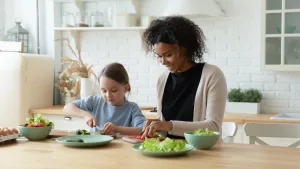 A young girl and her Au Pair chop vegetables in the kitchen