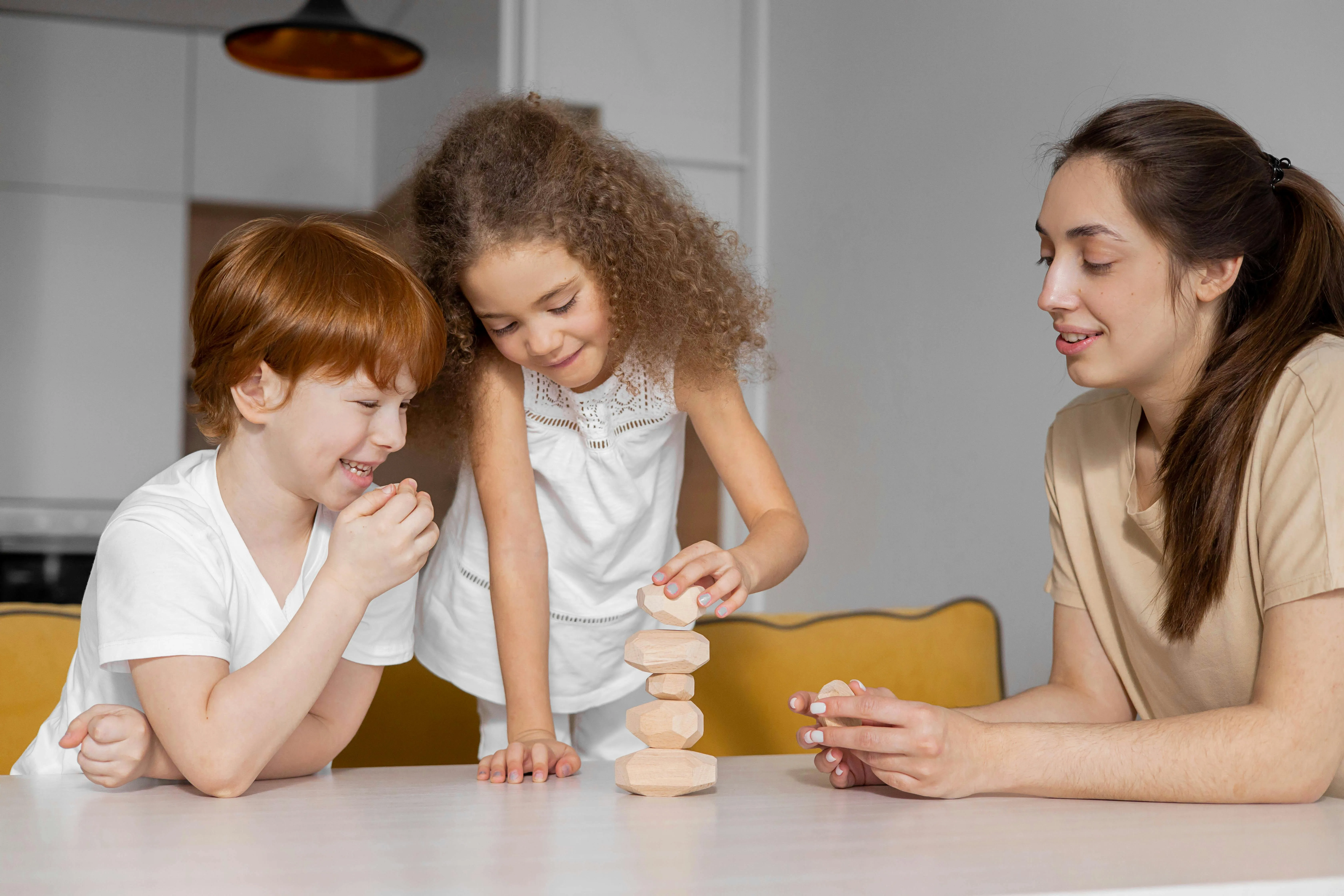 Au Pair and children playing with blocks at a table