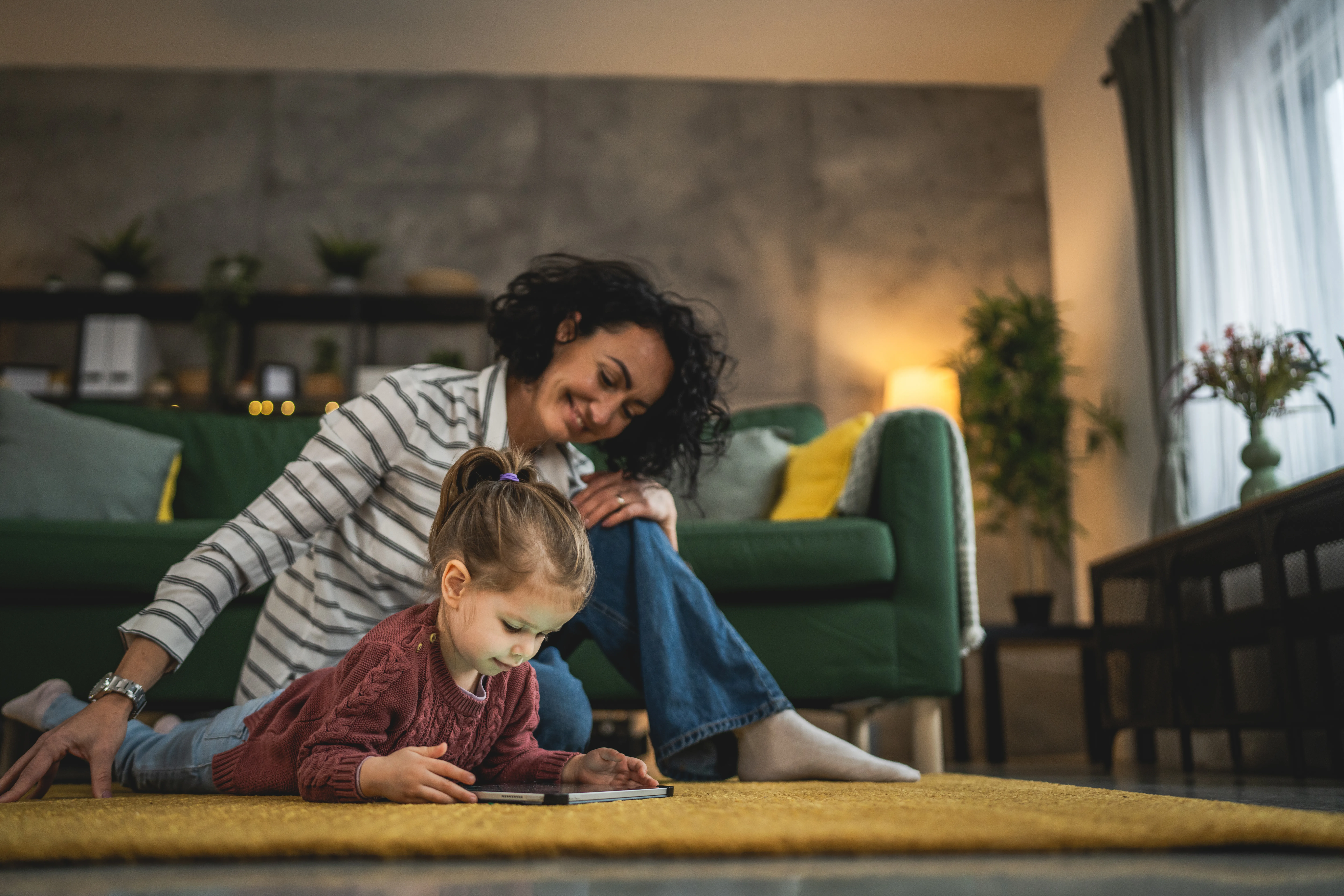 Mother and daughter use digital tablet to watch online video at home