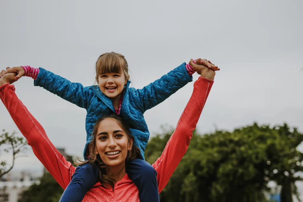 An Au Pair carries her young ward on her shoulders.