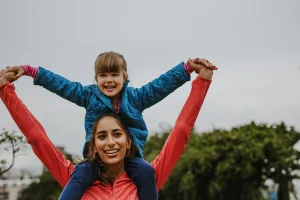 An Au Pair carries her young ward on her shoulders.