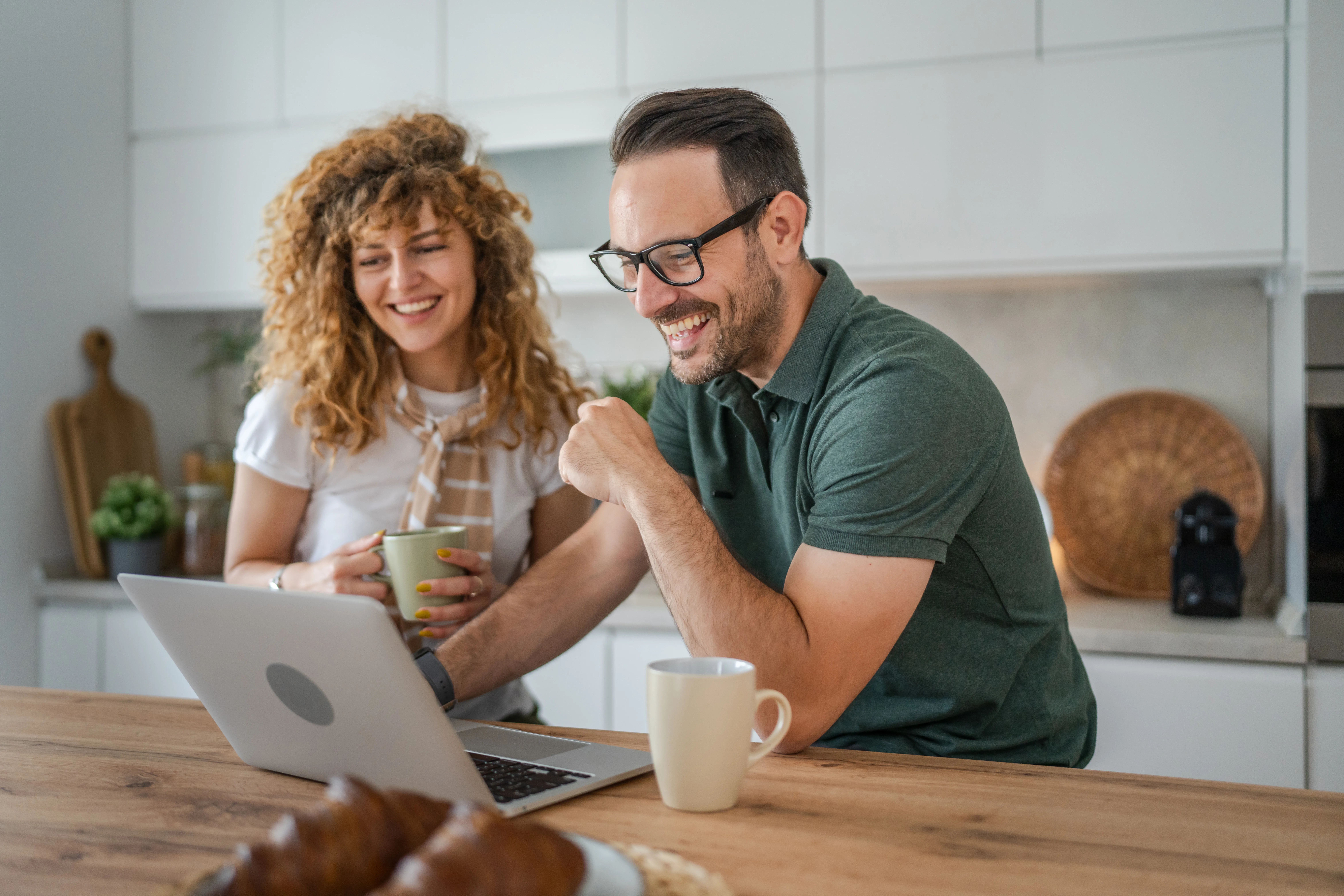 happy couple caucasian adult man and woman husband and wife morning routine use laptop computer during breakfast at home bright photo copy space
