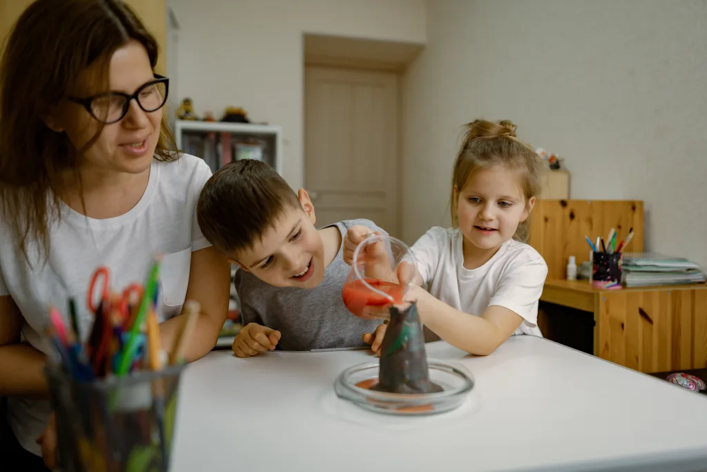 An Au Pair assists two young children with STEM activities.