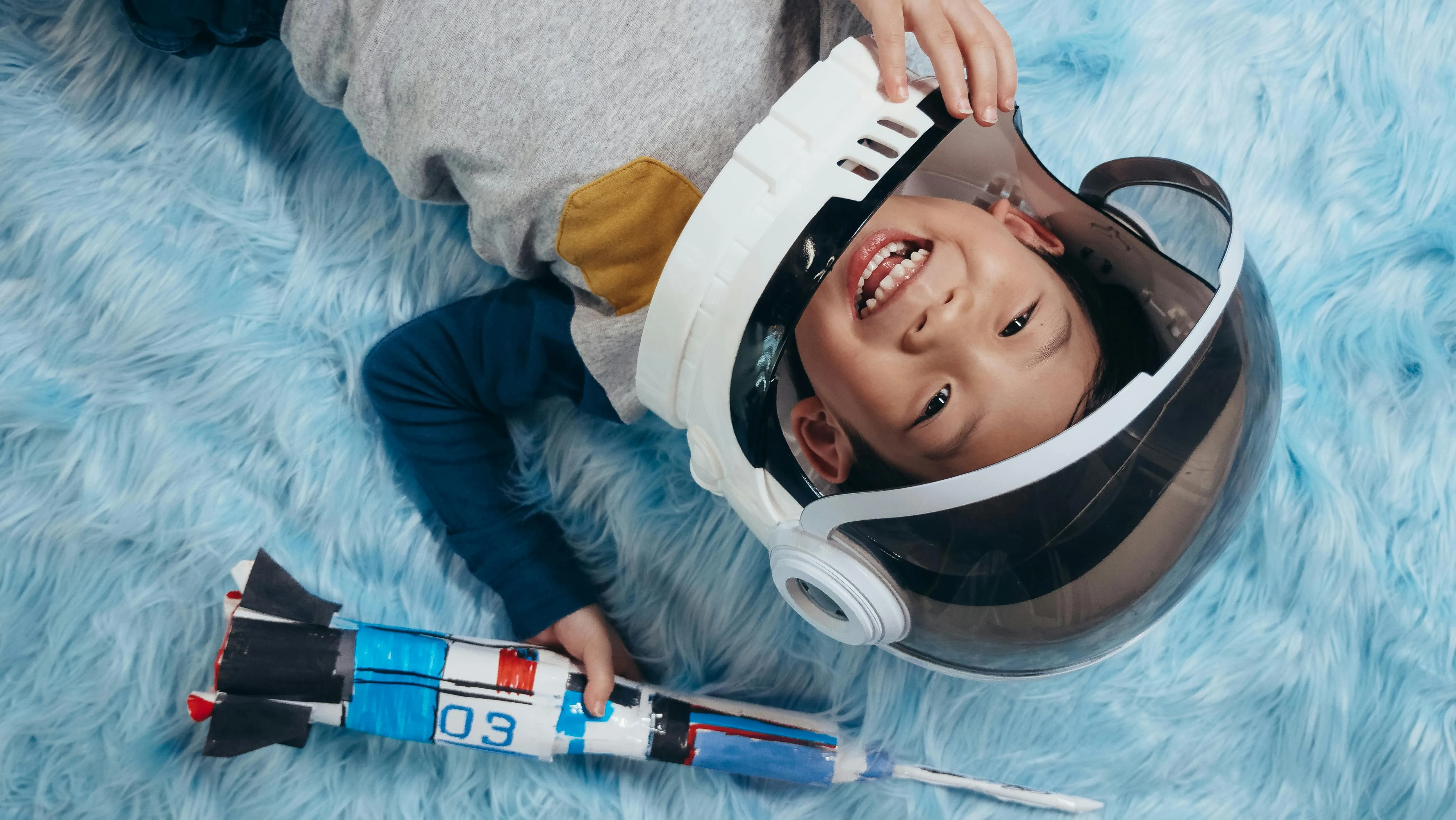 Child wearing astronaut helmet and playing with a space ship