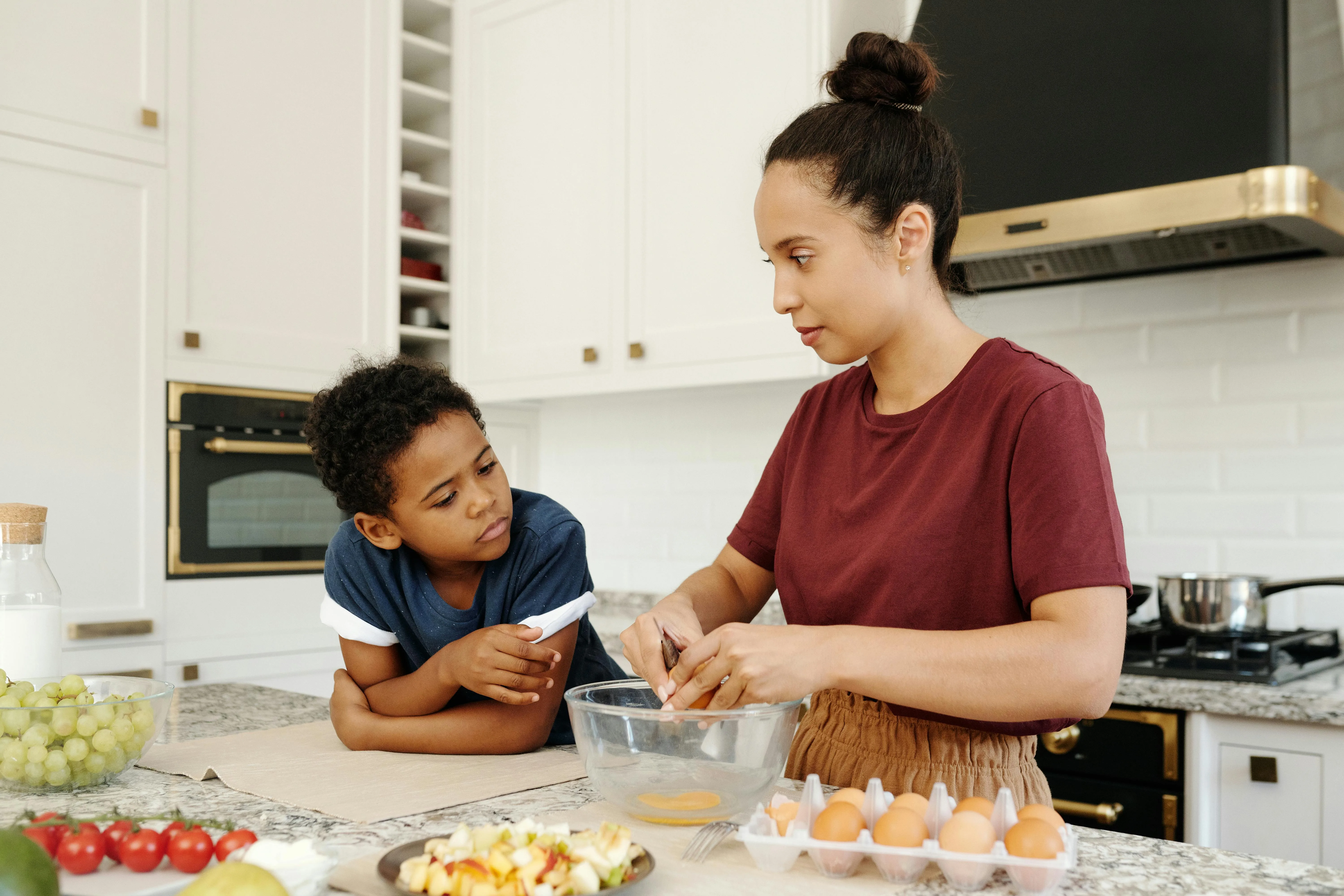 Au Pair and child crack eggs in to a bowl